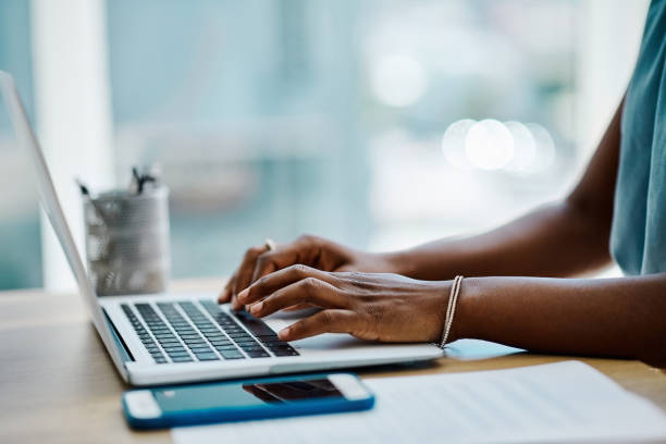 Closeup of a black businesswoman typing on a laptop keyboard in an office alone Closeup of a black businesswoman typing on a laptop keyboard in an office alone